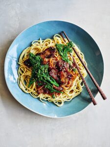 Sticky Mongolian beef noodles in a blue bowl with chopsticks