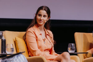 Chanel Contos on stage. She is looking to the left of screen, sitting down.